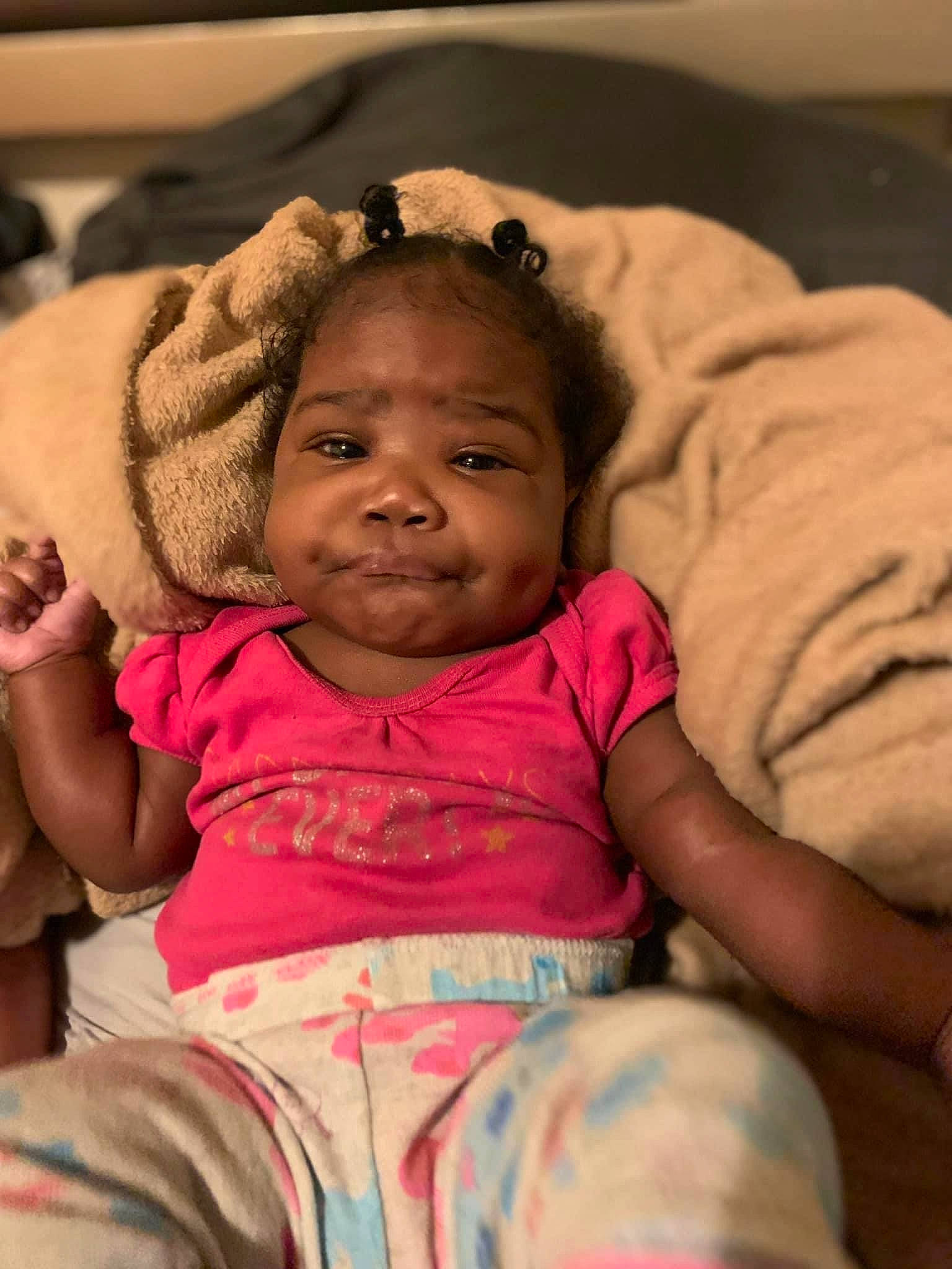 Janae is registered to the contest to win money with this photo: baby, baby_toddler_clothing, cheek, child, comfort, eye, finger, hair, happy, head, iris, linens, lip, mouth, nose, person, pink, sitting, skin, smile