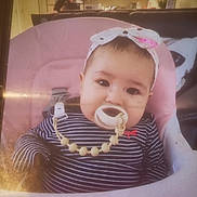 Ella Rose joined the competition — help win amazing prizes! baby, pacifier, headband, striped_shirt, pink_chair, infant, indoors, person, face, child, seated, cute, home, living_room, furniture, clothing, young_child, smiling, portrait, domestic