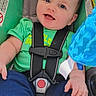 baby, child, car_seat, green_shirt, blue_pants, smiling, happy, infant, seatbelt, toy, blue_toy, cute, portrait, sitting, foot, hand, indoor, safety, young_child, face