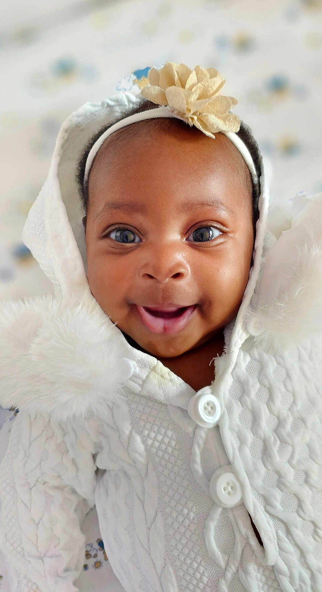 Peace joined the competition — help win amazing prizes! baby, smiling, close_up, white_clothing, headband, flower, hood, knitwear, happy, infant, cute, portrait, child, face, eyes, buttoned_clothing, soft_texture, indoor, warm, adorable