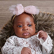 Peace is registered to the contest to win money with this photo: baby, infant, headband, pink_bow, lace, clothing, fur_cushion, portrait, indoor, cute, child, skin, face, eyes, hands, newborn, fashion, adorable, young, expression