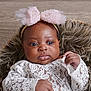baby, infant, headband, pink_bow, lace, clothing, fur_cushion, portrait, indoor, cute, child, skin, face, eyes, hands, newborn, fashion, adorable, young, expression