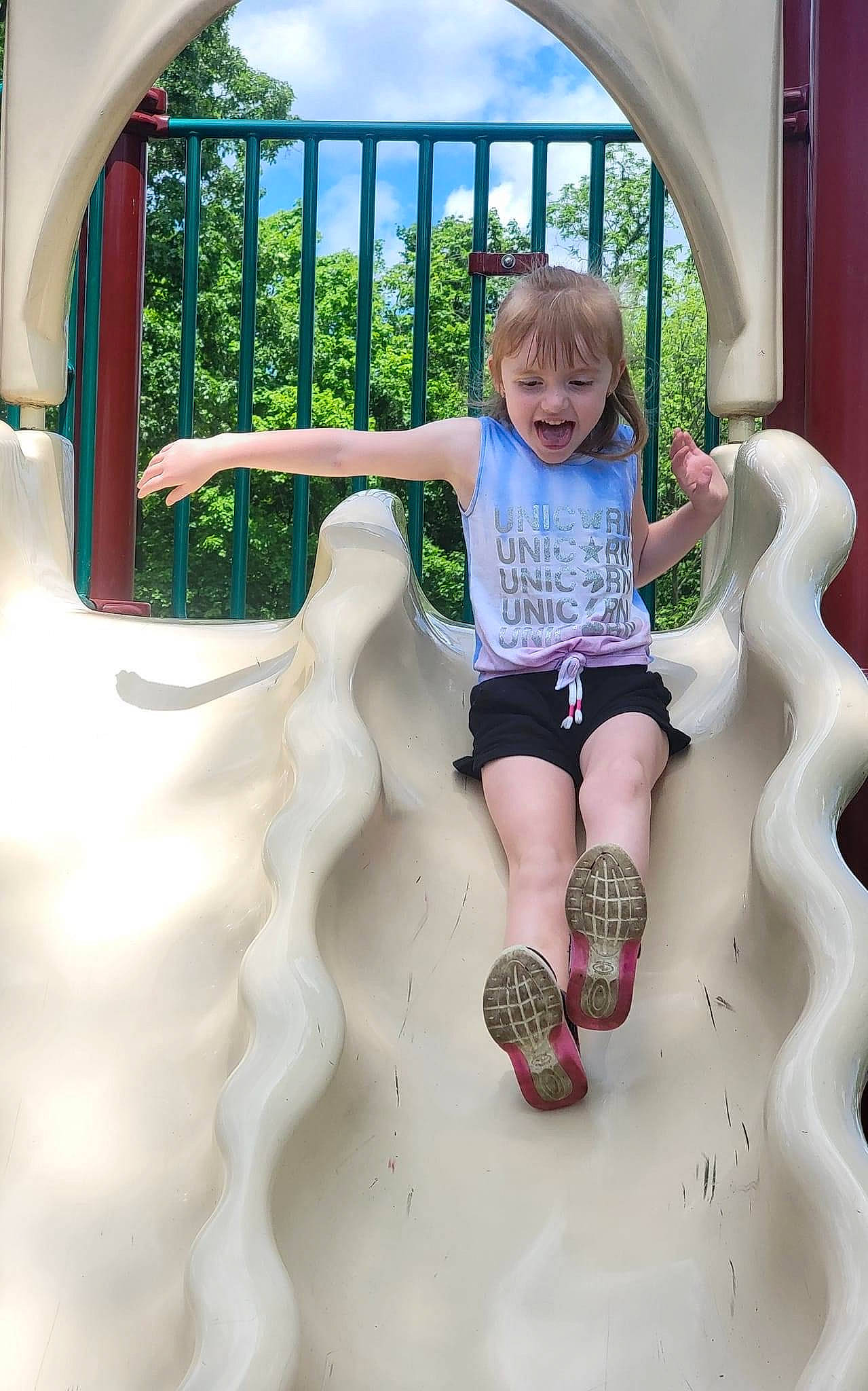 Peyton is registered to the contest to win money with this photo: chute, city, cool, fun, green, happy, knee, leisure, outdoor_play_equipment, person, playground, playground_slide, recreation, shorts, smile, summer, t_shirt, thigh, toddler, tree