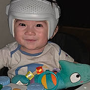 Mylo is registered to the contest to win money with this photo: toddler, child, helmet, smile, face, toy, plush_toy, activity_center, xylophone, colorful, indoor, clothing, happy, person, infant, cute, baby, playtime, headgear, seated