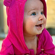 Violet is registered to the contest to win money with this photo: adorable, baby, blue_eyes, bokeh, cheeks, child, closeup, clothing, cute, fist, gaze, happy, hood, indoor, infant, pink_hoodie, portrait, skin, smile, soft_texture