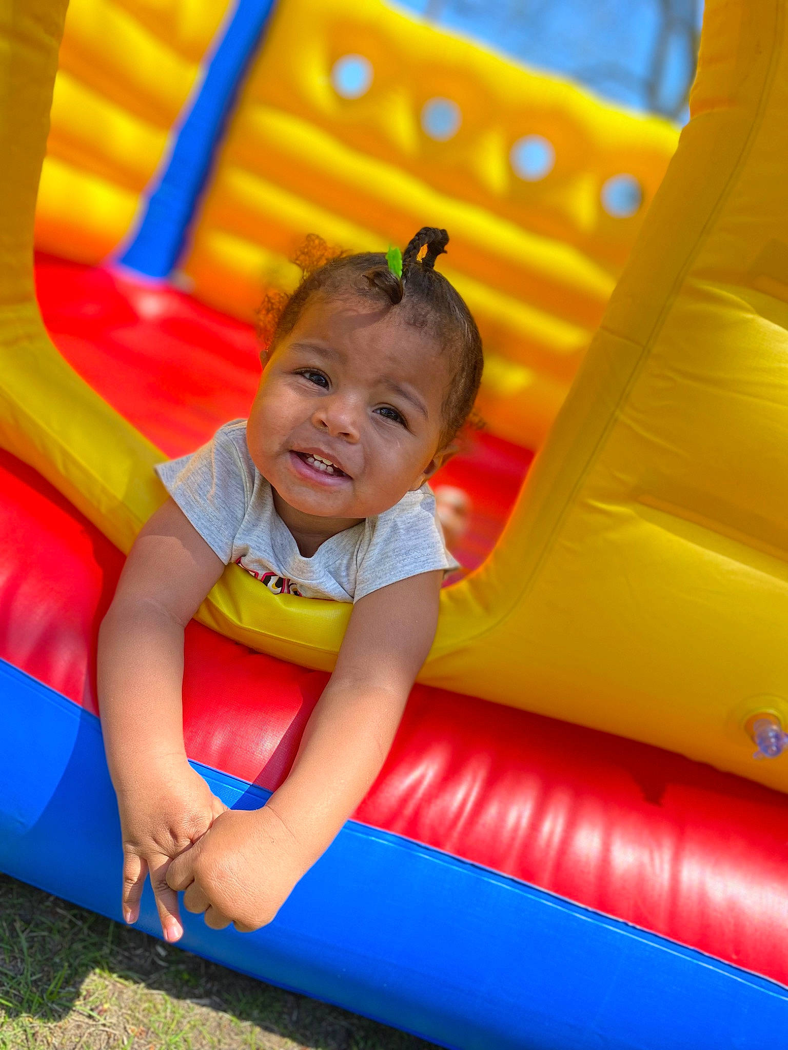 Jaziyah is registered to the contest to win money with this photo: baby, baby_toddler_clothing, bounce_house, child, chute, comfort, electric_blue, fun, grass, happy, inflatable, leisure, outdoor_play_equipment, person, play, playground, recreation, sitting, smile, symmetry