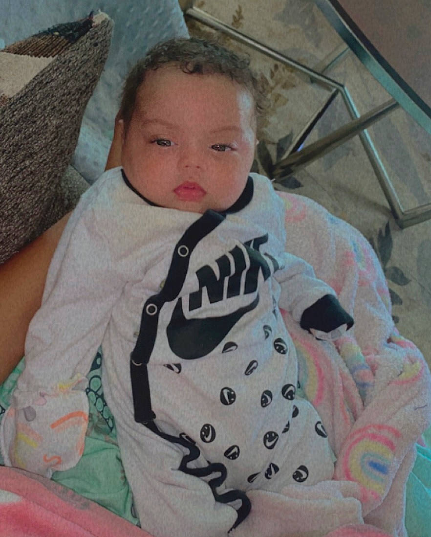 Jazmyn joined the competition — help win amazing prizes! baby, baby_products, baby_toddler_clothing, chair, cheek, child, comfort, eyelash, iris, linens, neck, nose, outerwear, pattern, person, sitting, skin, sleeve, t_shirt, textile