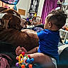 baby, dog, infant, pet, cuddle, indoors, bedroom, bed, blue_shirt, brown_dog, sitting, toys, baby_toy, family, companion, portrait, purple_curtains, furniture, home, playtime