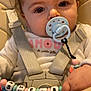 Shelby participe au concours pour gagner de l'argent avec cette photo : baby, pacifier, high_chair, beads, name_chain, child, infant, cute, closeup, straps, white_clothing, pink_letters, hand, face, eyes, hair, indoors, seatbelt, toy, soft_lighting