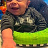 Maxamus is registered to the contest to win money with this photo: baby, smiling, child, infant, reaching, baby_seat, toy, striped_clothing, happy, face, hand, indoor, person, young_child, playful, closeup, cute, expression, seat, background