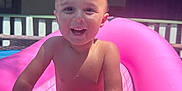Ej. is registered to the contest to win money with this photo: child, toddler, smiling, water, pool, inflatable_toy, pink, sunlight, outdoor, summer, happy, play, skin, hand, face, backyard, water_droplets, fun, daytime, climbing