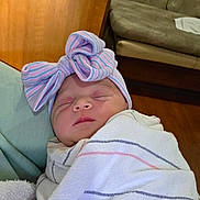 Adalynn is registered to the contest to win money with this photo: newborn, baby, sleeping, swaddled, bow, hat, hospital_blanket, blanket, baby_face, closed_eyes, infant, peaceful, portrait, indoors, couch, sofa, wood_paneling, headwear, soft_texture, wrapped