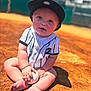 baby, baseball, baseball_field, child, sportswear, hat, cap, outdoor, sunlight, dirt, grass, portrait, sitting, cute, infant, holding, smiling, person, playful, team_uniform