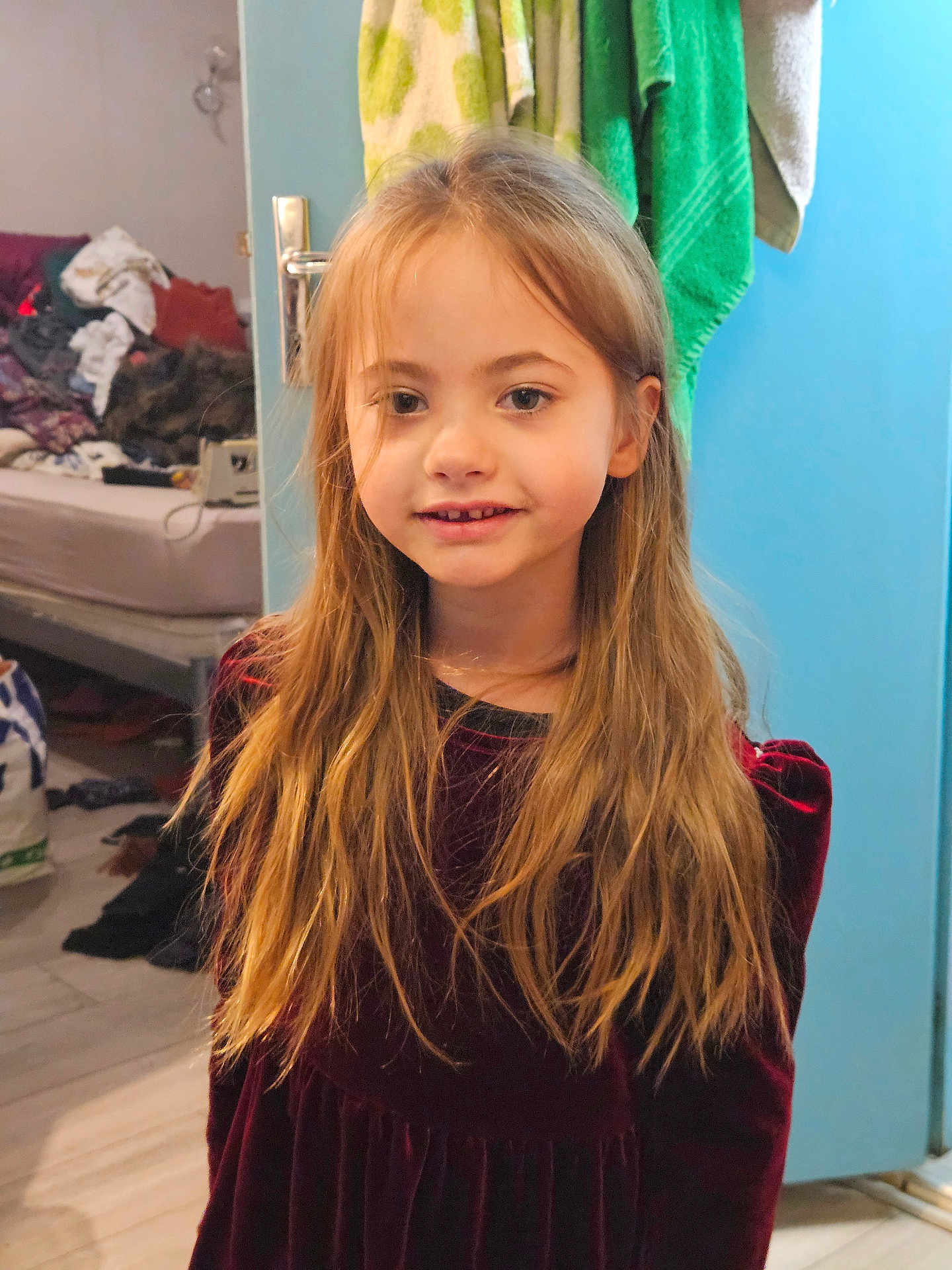 Lana participe au concours pour gagner de l'argent avec cette photo : child, girl, blonde_hair, long_hair, smile, dress, velvet, indoor, door, towel, bed, clutter, room, floor, person, portrait, casual, young, standing, human