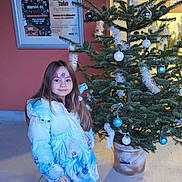 Lana a rejoint le concours — aidez-le/la à gagner de superbes lots ! brown_shoes, child, christmas_tree, concrete_floor, decoration, face_painting, festive, girl, holiday_decor, long_hair, ornaments, outdoor, person, pink_pants, poster, seasonal, smile, window, winter_coat, young