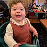 Blakely joined the competition — help win amazing prizes! toddler, child, smiling, curly_hair, high_chair, restaurant, indoor, person, clothing, table, chair, people, happy, baby, cute, portrait, dining, seat, casual, family