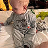 Odin is registered to the contest to win money with this photo: toddler, child, bed, pajamas, grey_clothing, plush_toy, blanket, person, smiley_pants, indoors, bedroom, white_bedspread, cute, sitting, looking_down, cozy, young_child, footwear, furniture, casual_wear
