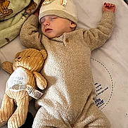 Odin is registered to the contest to win money with this photo: baby, sleeping, onesie, hat, plush_toy, teddy_bear, blanket, soft, infant, cozy, cute, child, peaceful, bed, resting, indoors, comfort, warm, adorable, toy