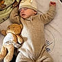 baby, sleeping, onesie, hat, plush_toy, teddy_bear, blanket, soft, infant, cozy, cute, child, peaceful, bed, resting, indoors, comfort, warm, adorable, toy