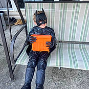 John Landon joined the competition — help win amazing prizes! child, batman_costume, mask, orange_bucket, outdoor_swing, striped_fabric, concrete_floor, sandals, superhero, costume, smile, play, toy_container, childhood, casual, relaxing, daylight, home, fun, pretend_play