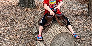 John Landon joined the competition — help win amazing prizes! child, boy, red_shirt, spiderman, sandal, wood_log, saddle, outdoor, playground, tree, leaves, wood_chips, pretend_play, nature, casual_clothing, daytime, forest, fun, childhood, recreation