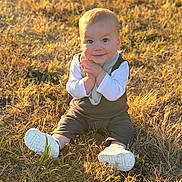 Liam joined the competition — help win amazing prizes! baby, child, grass, outdoor, sunlight, smile, sitting, white_shoes, clothing, nature, happy, portrait, infant, young_child, daylight, field, casual, face, scarf, playful