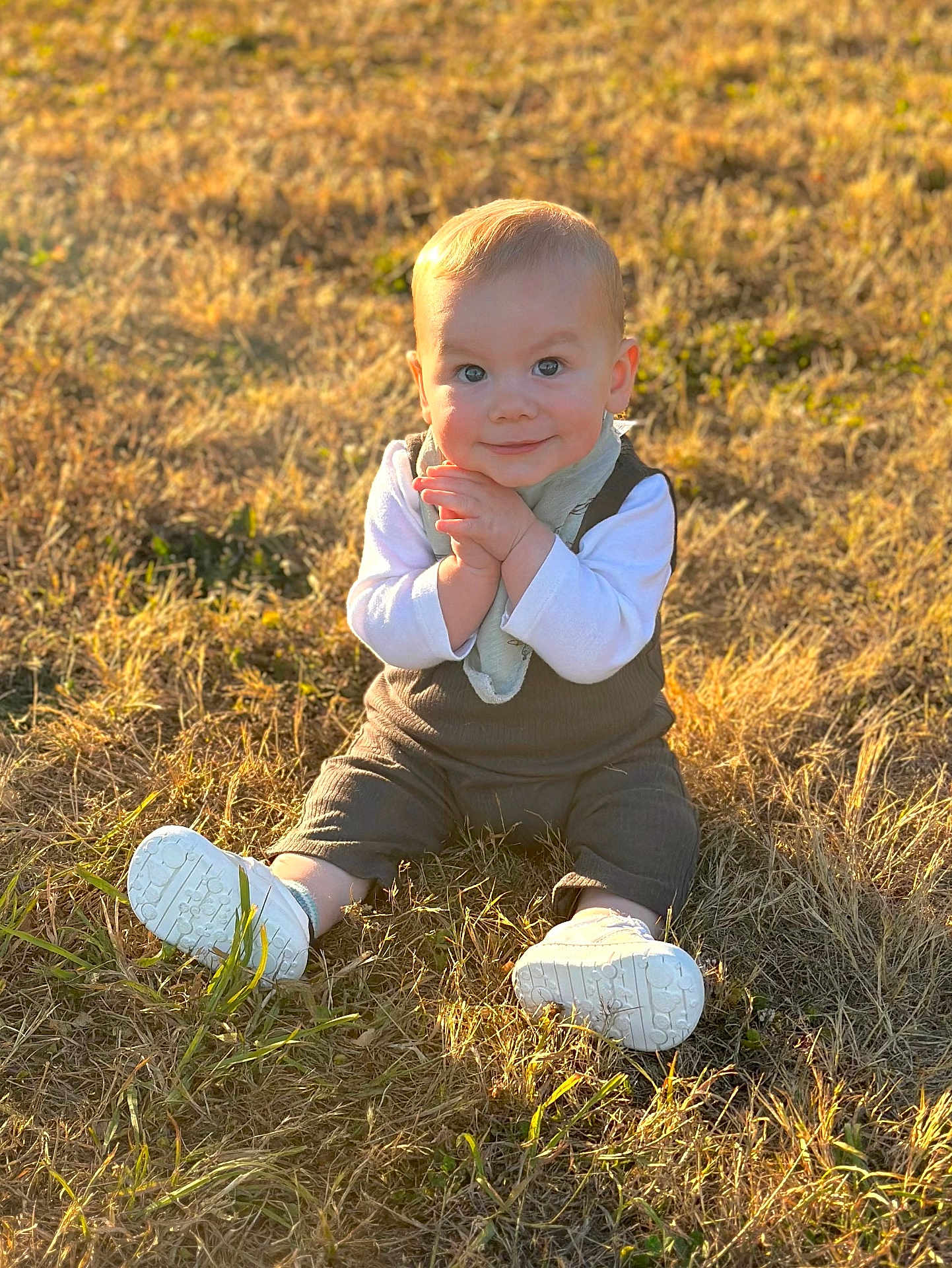 Liam joined the competition — help win amazing prizes! baby, child, grass, outdoor, sunlight, smile, sitting, white_shoes, clothing, nature, happy, portrait, infant, young_child, daylight, field, casual, face, scarf, playful