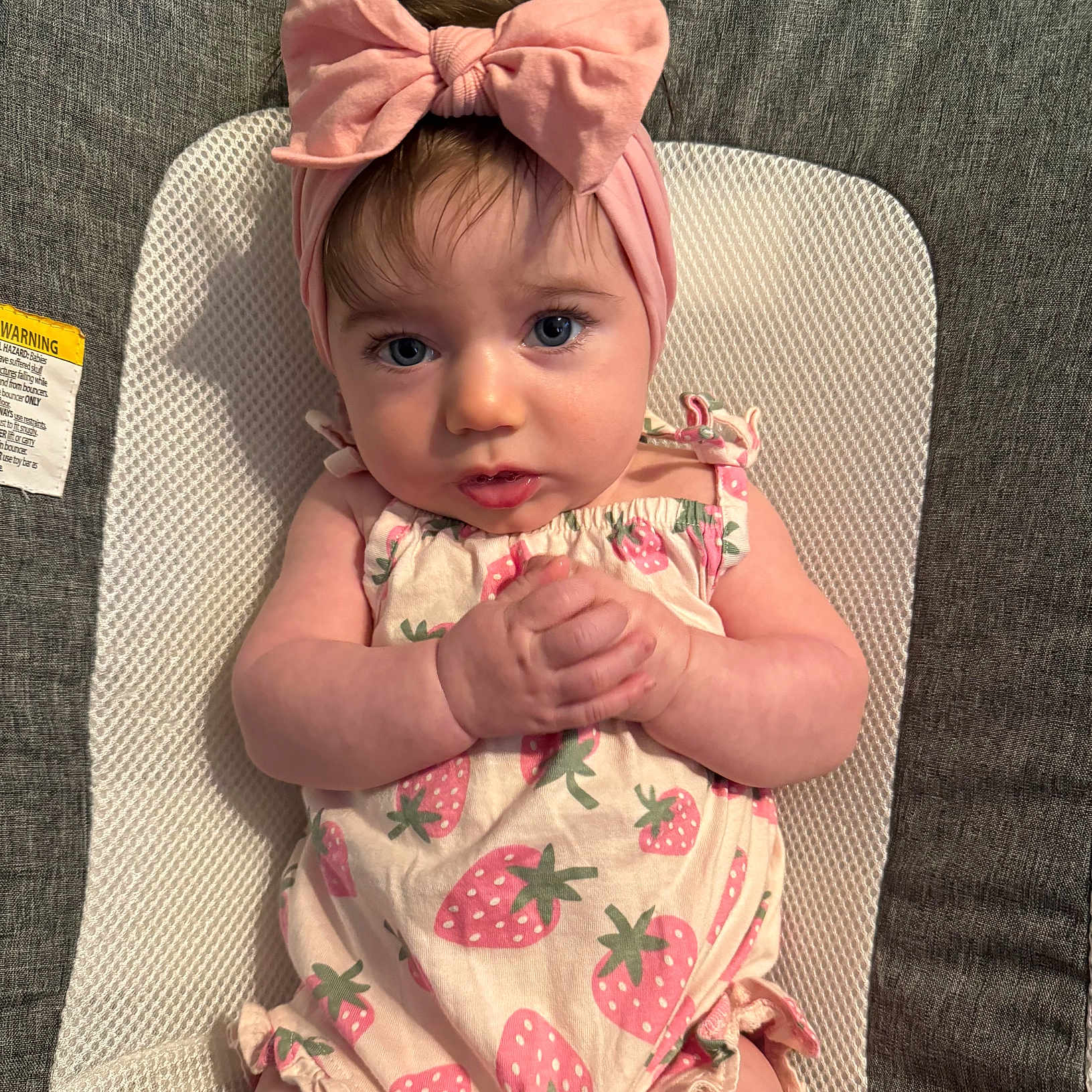Maddie joined the competition — help win amazing prizes! baby, headband, pink_bow, infant, strawberry_print, clothing, hands, face, blue_eyes, cute, portrait, lying_down, fabric, texture, child, soft_lighting, expression, close_up, person, young_child