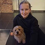 Boyka a rejoint le concours — aidez-le/la à gagner de superbes lots ! black_hoodie, casual, child, companion, cozy, curly_hair, decor, dog, floor, friendly, happy, home, indoor, pet, portrait, small_dog, smiling, tile_floor, wood_stack, young