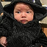 baby, child, costume, black_fur, hood, cute, face, expression, indoor, person, hand, purple_eyes, clothing, portrait, curious, soft_texture, tattoo, background, table, can