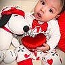 baby, child, valentines_day, plush_toy, snoopy, heart, red_bow, pajamas, cute, indoor, couch, stuffed_animal, smiling, portrait, love, holiday, childhood, toy, infant, happy