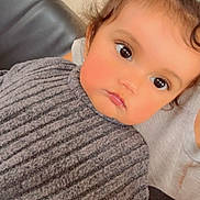 Kaissy participe au concours pour gagner de l'argent avec cette photo : child, toddler, face, eyes, hair, curly_hair, sweater, gray_sweater, ribbed_sweater, portrait, indoor, couch, leather_couch, person, closeup, cute, expression, topknot, skin, young
