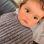 child, toddler, face, eyes, hair, curly_hair, sweater, gray_sweater, ribbed_sweater, portrait, indoor, couch, leather_couch, person, closeup, cute, expression, topknot, skin, young