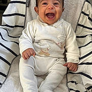 Martin a rejoint le concours — aidez-le/la à gagner de superbes lots ! baby, infant, smile, happy, child, white_clothing, striped_blanket, cushion, seated, indoors, cute, person, young_child, face, expression, furniture, soft_texture, portrait, small_hands, footed_pajamas