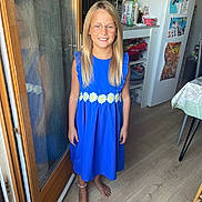 Shelby a rejoint le concours — aidez-le/la à gagner de superbes lots ! child, girl, blue_dress, glasses, barefoot, kitchen, wooden_floor, refrigerator, plants, reflection, smiling, long_hair, indoors, home, furniture, door, table, decorations, casual, portrait
