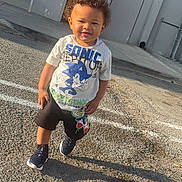 Ryan joined the competition — help win amazing prizes! child, toddler, boy, sonic_the_hedgehog, tshirt, shorts, sneakers, outdoor, parking_lot, shadow, sunlight, curly_hair, building, bench, concrete, sidewalk, smiling, standing, daytime, casual_clothing