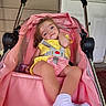 Emerson is registered to the contest to win money with this photo: toddler, stroller, pink, yellow_outfit, socks, child, baby, seatbelt, porch, door, relaxed, curious, infant, outdoor, baby_carriage, person, casual, comfort, young_child, baby_girl