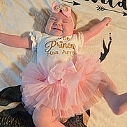 Jessica joined the competition — help win amazing prizes! baby, infant, girl, smiling, tutu, pink, headband, bow, blanket, text, happy, lying_down, cute, clothing, arms_up, legs, soft_texture, indoor, child, portrait