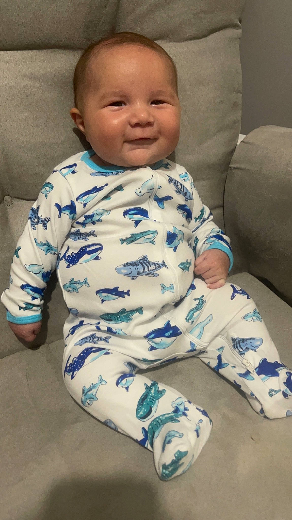 Jace is registered to the contest to win money with this photo: baby, baby_toddler_clothing, cheek, child, collar, comfort, electric_blue, face, flooring, happy, human_leg, joy, knee, linens, pattern, person, sitting, skin, sleeve, smile