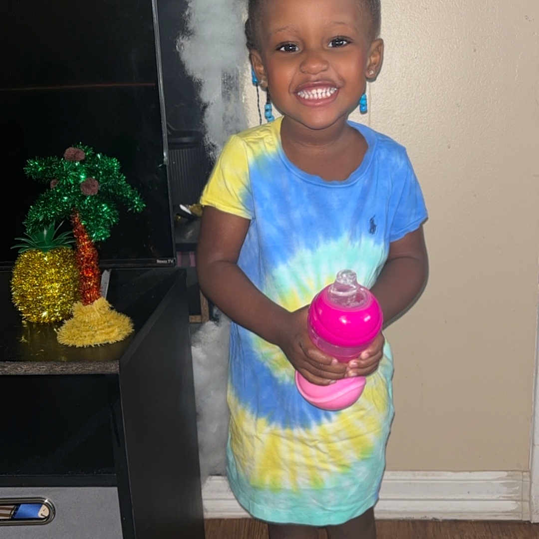 Khloe joined the competition — help win amazing prizes! bottle, child, clothing, cream, dessert, dress, face, female, footwear, girl, head, person, photography, plant, portrait, pottedplant, purple, sandal, shaker, shoe