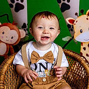 Mateo joined the competition — help win amazing prizes! baby, child, smiling, wicker_chair, bow_tie, suspenders, jungle_theme, monkey, giraffe, green_background, paw_prints, cute, portrait, happy, indoor, decorations, toddler, clothing, person, seated