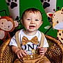 baby, child, smiling, wicker_chair, bow_tie, suspenders, jungle_theme, monkey, giraffe, green_background, paw_prints, cute, portrait, happy, indoor, decorations, toddler, clothing, person, seated