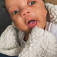 Liam joined the competition — help win amazing prizes! baby, infant, face, blanket, closeup, cute, child, expression, skin, mouth, eyes, curly_hair, white_clothing, soft_texture, indoors, portrait, newborn, young_child, wrapped, cozy