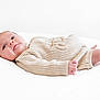 baby, infant, lying_down, knitted_clothing, beige, white_background, soft_light, portrait, cute, newborn, child, small_hands, small_feet, cozy, warm_clothing, relaxed, indoor, close_up, sleepwear, peaceful