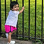 Veena joined the competition — help win amazing prizes! toddler, child, smiling, white_shirt, pink_shorts, sneakers, outdoor, grass, fence, happy, playful, young_child, person, casual_clothing, summer, daylight, standing, cute, park, metal_fence