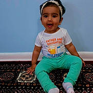 Veena is registered to the contest to win money with this photo: toddler, child, sitting, carpet, headband, shirt, pants, socks, wall, floor, indoor, smiling, happy, portrait, person, cute, clothing, baby, home, young