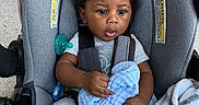 Akyrie is registered to the contest to win money with this photo: baby, blanket, car_seat, child, closeup, clothing, comfort, curly_hair, cute, expression, foot, hands, indoor, infant, pacifier, person, seatbelt, sitting, soft_texture, toddler
