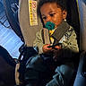 baby, child, car_seat, pacifier, infant, seat_belt, clothing, socks, indoors, person, young_child, portrait, cute, warm_light, baby_clothes, seat, child_safety, hands, face, hair