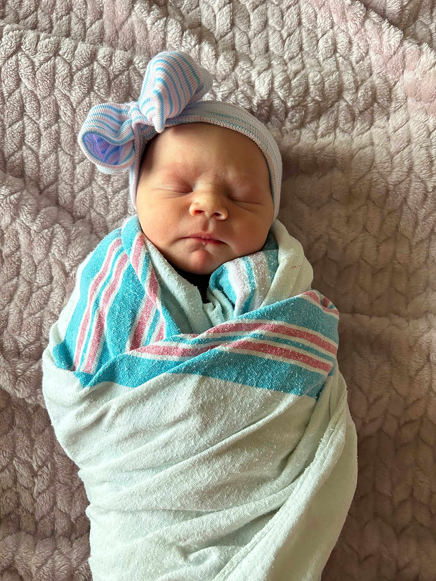 Paisley is registered to the contest to win money with this photo: newborn, baby, sleeping, wrapped, blanket, hat, bow, striped, pastel_colors, soft_texture, cozy, indoors, portrait, infant, headwear, peaceful, cute, resting, person, child
