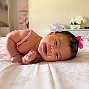 Ella joined the competition — help win amazing prizes! baby, infant, smiling, happy, pink_bow, bed, indoor, child, cute, portrait, skin, face, person, young, lying, head, arm, furniture, soft_light, cozy